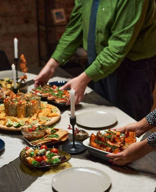 Close-up of couple carrying different appetizers on dining table, they preparing for dinner party